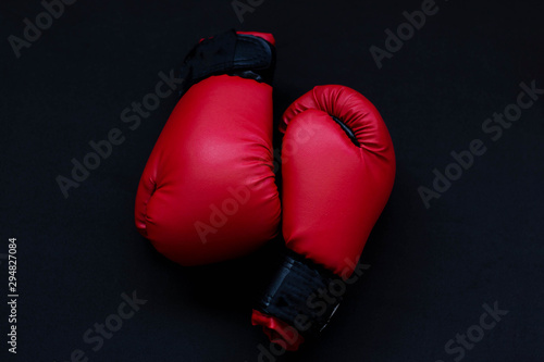 Red boxing gloves on a black background © Elena