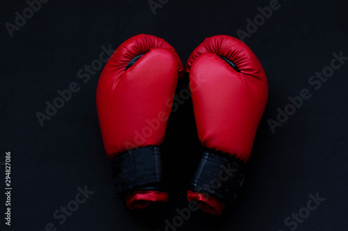 Red boxing gloves on a black background © Elena