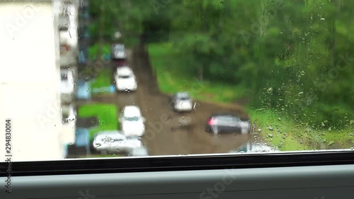 Drops of water flow down on the window glass. Summer rain in city. 4K video photo