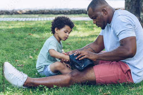 Canvas Print handsome african american man showing baseball glove to son while sitting on law