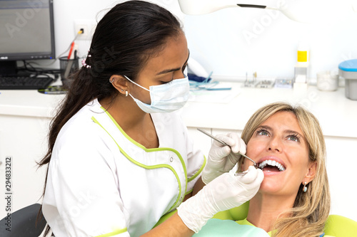 Female doctor dentist of Latin ethnicity attending a patient of Caucasian ethnicity.