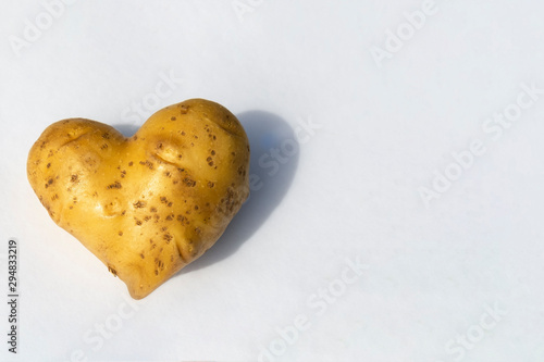 potatoes in the shape of a heart on a white background. expression of love with vegetables, potato lovers. place for text, copy space.