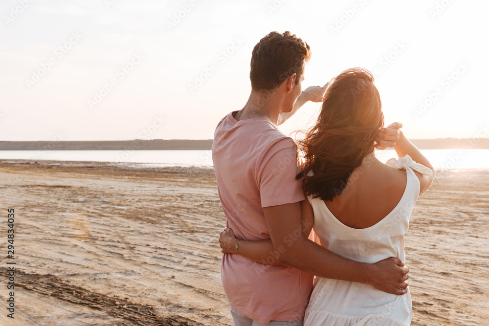 Beautiful young couple wearing summer clothing standing at the beach