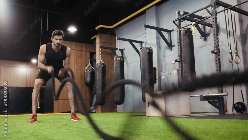 bearded man working out with suspension straps in gym