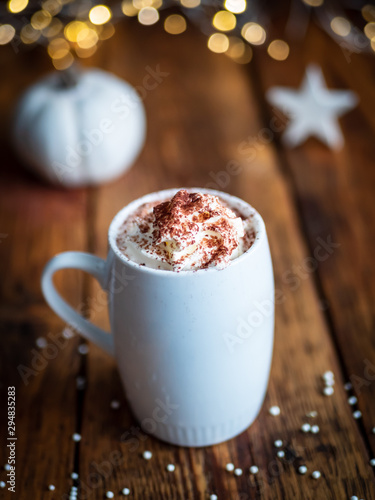 Heiße Schokolade mit Sahne in einer weißen Tasse auf einem braunen Holztisch, Weihnachtsdekoration