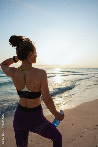 fitness woman with water on ocean coast in evening
