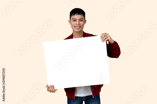 close up young asian ethnicity teenage man showing mockup blank poster (for add content) and smiling with happiness feeling isolated on cream color background for advertisement banner and billboard  photo