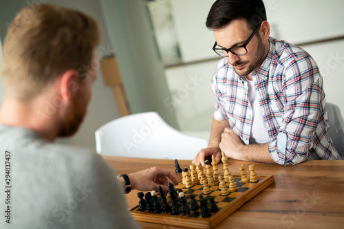 Young smart friends playing chess at home