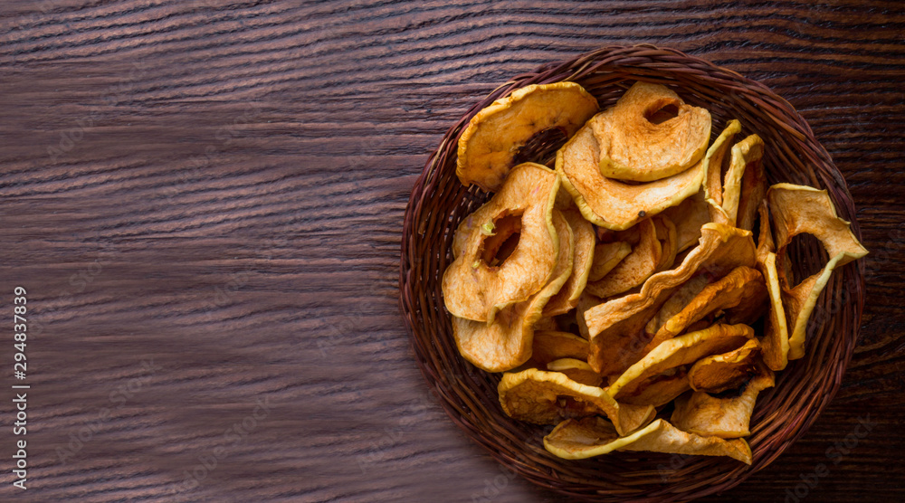 Fototapeta premium Top view of bowl with dried apple chips on wooden table