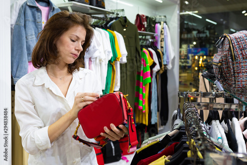 The girl chooses a red clatch in the store. photo