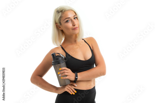 A sports girl with blonde hair and bright manicure holds a sports water bottle.