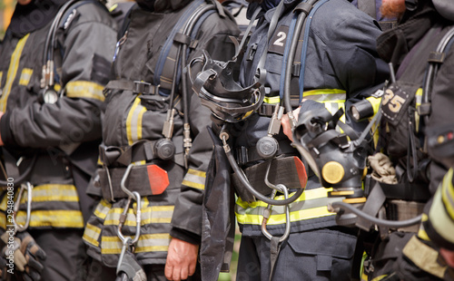 Several standing firefighters in special suits and gas masks