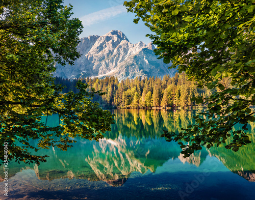 Calm morning view of Fusine lake. Colorful summer scene of Julian Alps with Mangart peak on background, Province of Udine, Italy, Europe. Beauty of nature concept background.