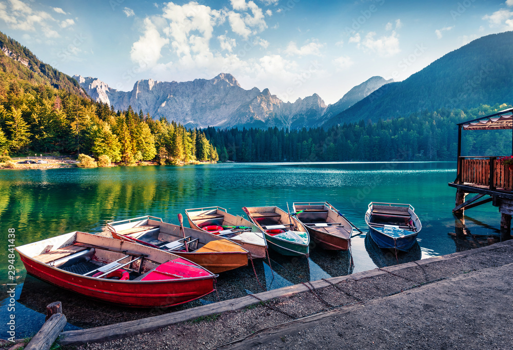 Six pleasure boats on Fusine lake. Splendid morning scene of Julian Alps with Mangart peak on background, Province of Udine, Italy, Europe. Traveling concept background.