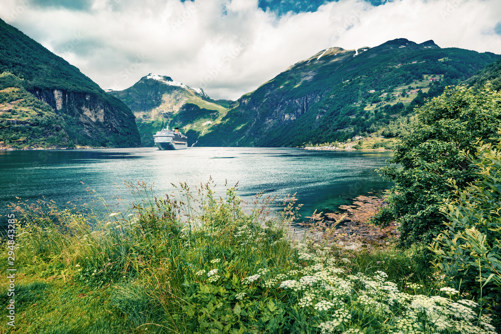 Gloomy summer scene of Geiranger port, western Norway. Colorful view of Sunnylvsfjorden fjord. Traveling concept background. Artistic style post processed photo.