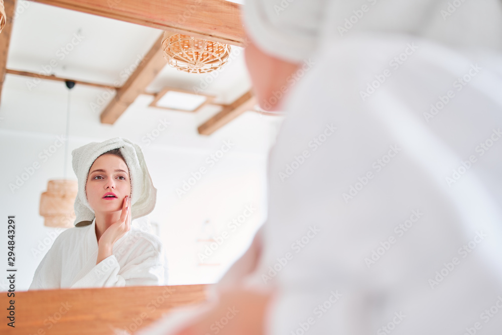 Photo of beautiful woman in bathrobe and with towel on her head reflected in mirror Photo of beautiful woman in bathrobe and with towel on her head reflected in mirror