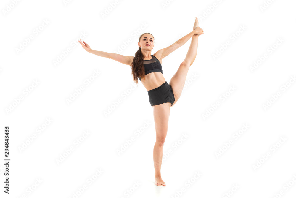 A beautiful young woman gymnast with dark long hair does warm-up and stretch her muscles.