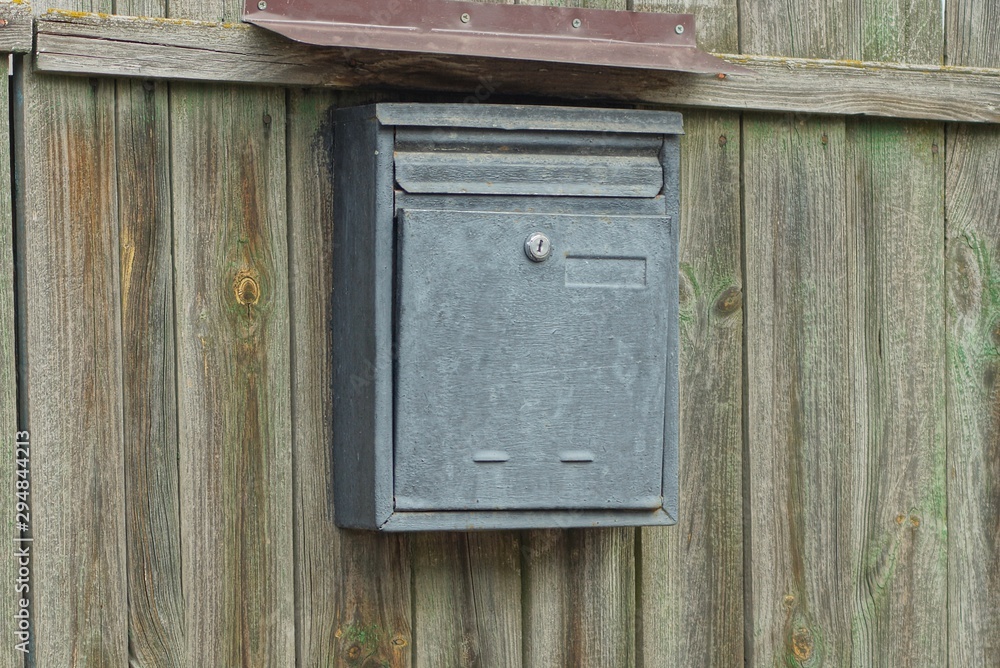 one gray metal mailbox hanging on a green wooden fence one gray metal mailbox hanging on a green wooden fence