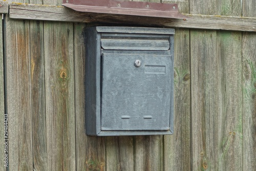 one gray metal mailbox hanging on a green wooden fence
