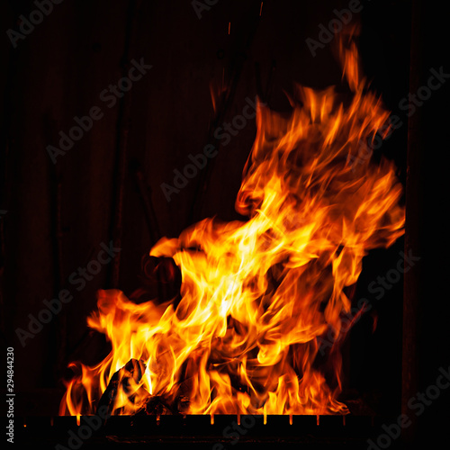 Fire flame on a dark background. Fire burning at night. A fire in the grill, fireplace and hearth.