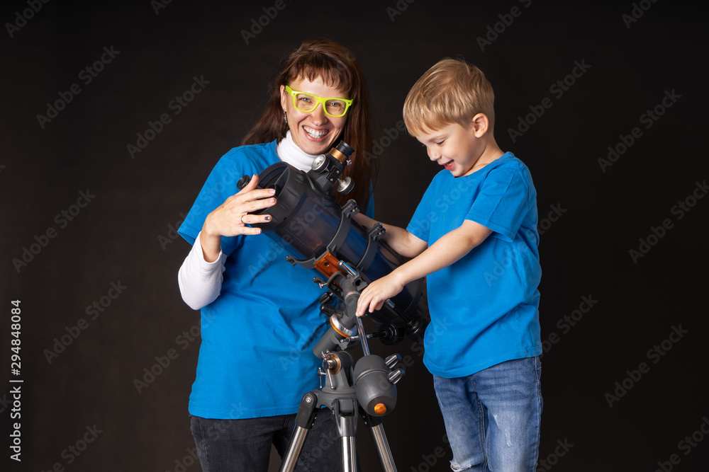 Mom and son are studying a large refractory telescope.