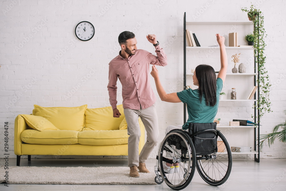 back view of young disabled woman in wheelchair dancing with happy boyfriend - obrazy, fototapety, plakaty 