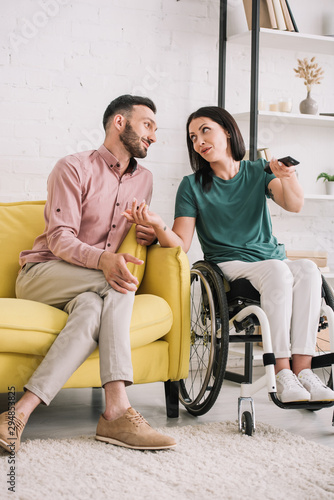 attractive disabled woman talking with handsome boyfriend while watching tv together at home