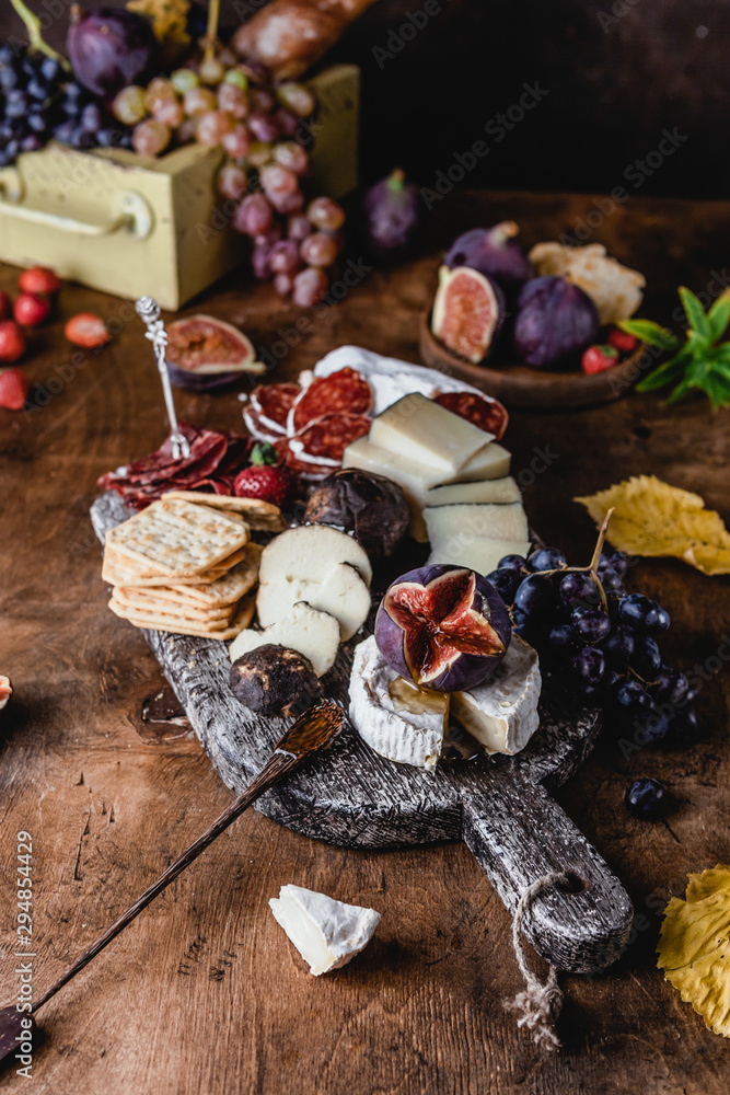 assortment of cheese on wooden board with fruits, honey and ham on brown wooden table, selective focus assortment of cheese on wooden board with fruits, honey and ham on brown wooden table, selective focus