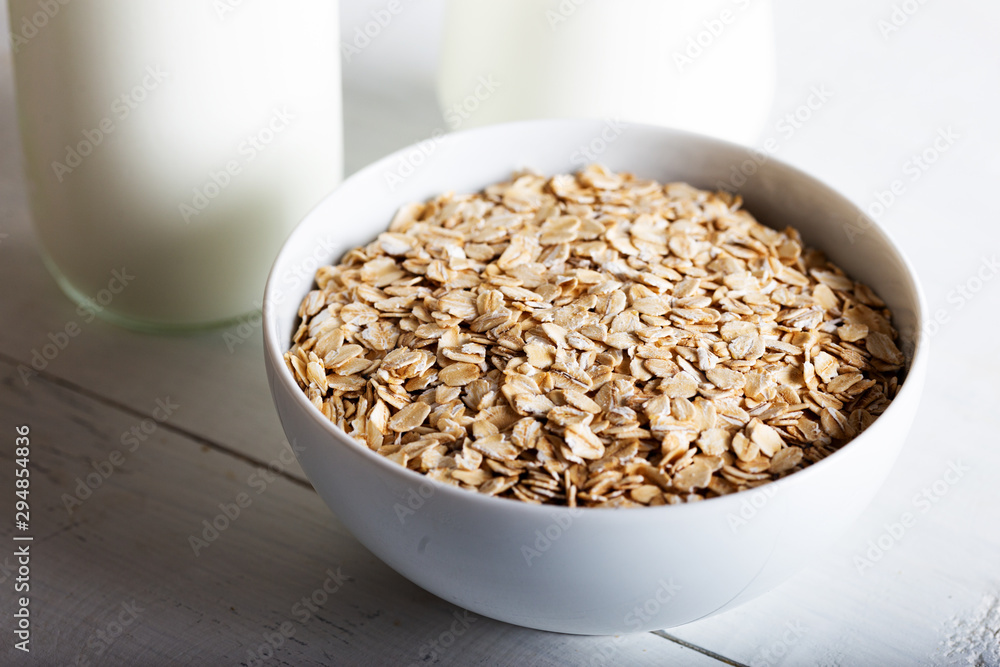 Oatmeal in a bowl with a bottle of milk on wooden background. Oatmeal in a bowl with a bottle of milk on wooden background.