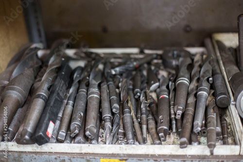 Abstract set of drill bits and metal drills on shelf in metallurgy workshop.