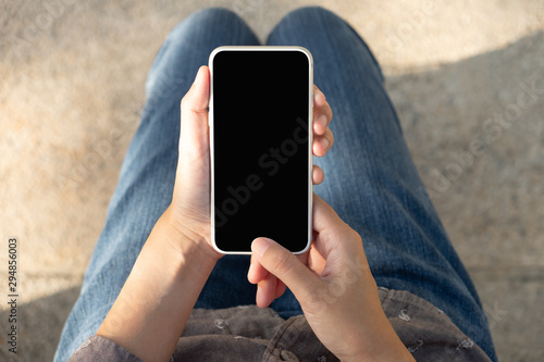 Woman hand holding and using smart phone with blank screen in the park