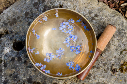 Tibetan bowl with small blue flowers floating on water
