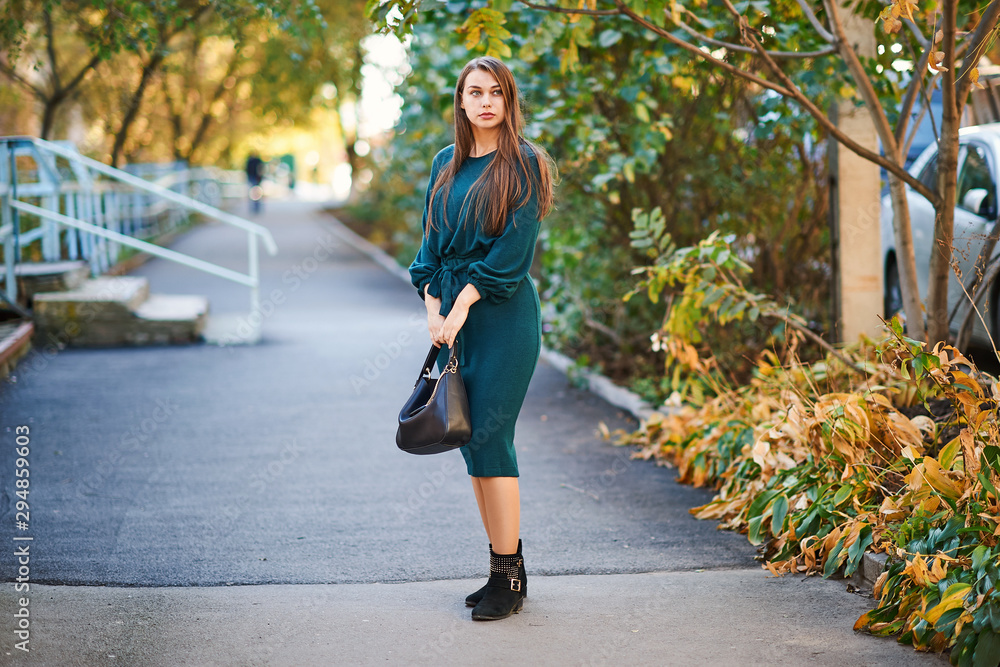 Serious woman in a green dress posing in the autumn alley Serious woman in a green dress posing in the autumn alley