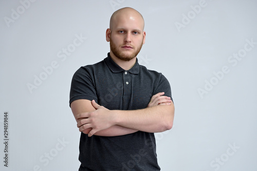 Slika na platnu Portrait of a handsome bald man in a gray t-shirt on a white background in the studio