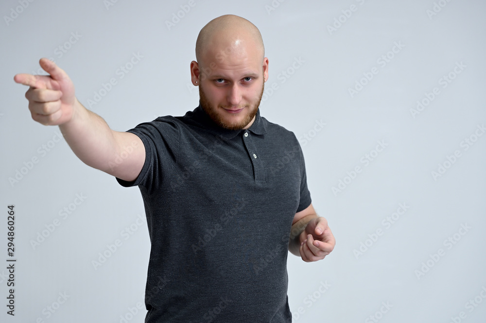 Portrait of a handsome bald man in a gray t-shirt on a white background in the studio. Shows emotions in various poses. Portrait of a handsome bald man in a gray t-shirt on a white background in the studio. Shows emotions in various poses.