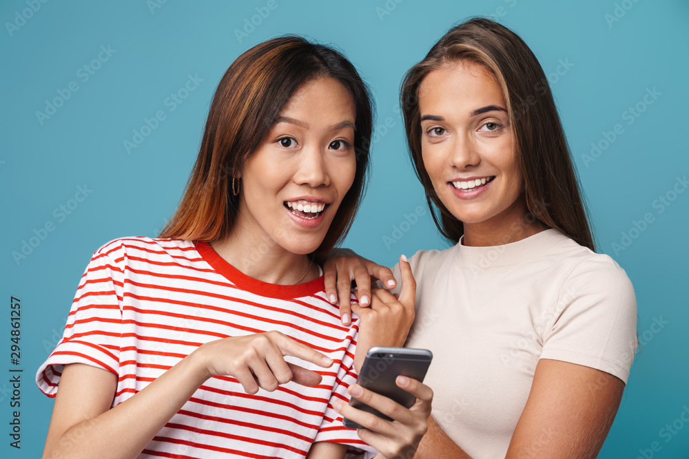 Portrait of smiling women holding and pointing finger at cellphone Portrait of smiling women holding and pointing finger at cellphone