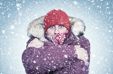 Frozen man in red winter clothes warms his hands, cold, snow, frost, blizzard 
