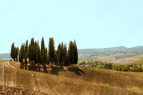 Typical landscapes for Siena Province in Tuscany, Italy. Cypress hills, plowed fields, roads and houses. Begining of autumn season.