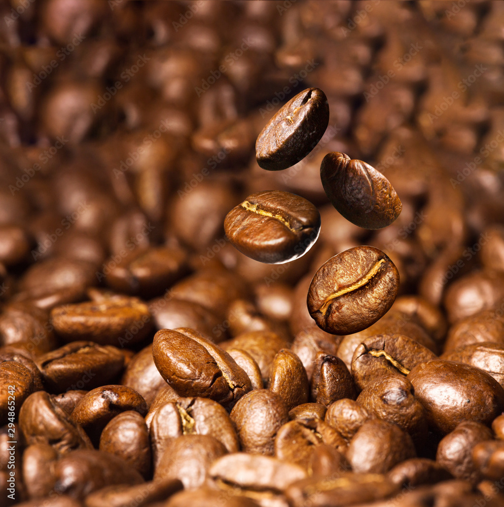 Fototapeta premium Roasted coffee beans. Seeds of freshly roasted coffee with smoke. Coffee beans closeup with emphasis on the grain with smoke.