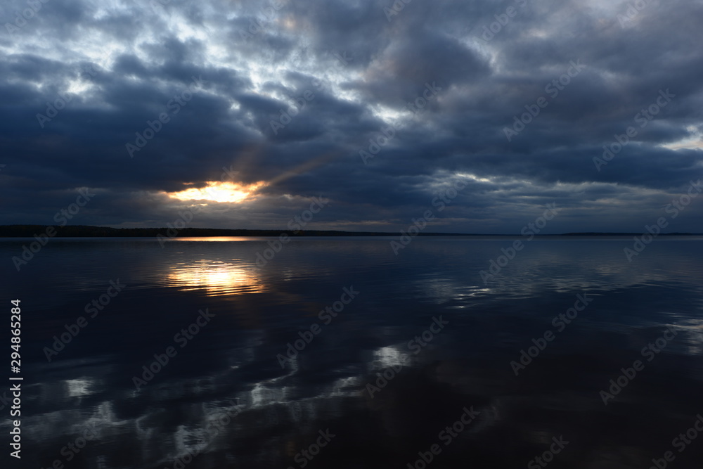 Cloudy blue sky at sunset in a bright beautiful glow of the sun's rays from the heavenly  sunlight clouds clearance reflects in the lake water