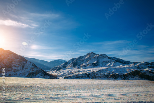Fantastic panorama of snow-covered plains and mountain slopes covered with snow on a frosty sunny winter day. Wild and desert places, road trips, Siberian expanses. © exebiche