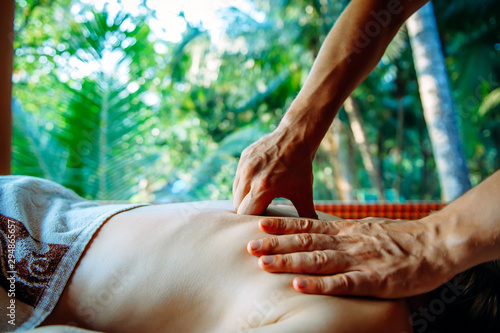 Acupressure massage in spa centre outdoor. Woman at acupressure back massage, masseur's hands close up. Body therapy for healthy lifestyle.