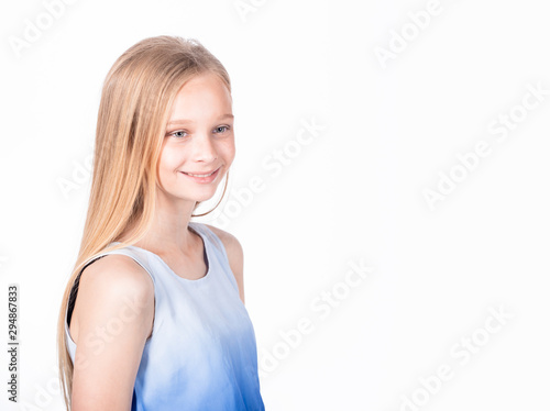 Charming happy young girl introducing herself to new classmates. Portrait of a pleased carefree adorable daughter with blond hair in white-blue blouse, standing casually and smiling friendly.