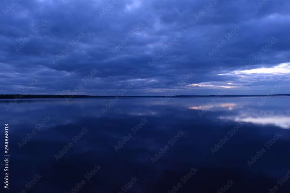 Dark beautiful blue space of clouds of sky and lake water in twilight in the silence and calm of an autumn evening