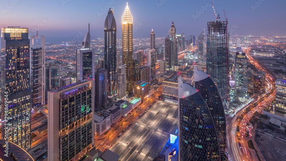 Obraz premium Skyline of the buildings of Sheikh Zayed Road and DIFC aerial day to night timelapse in Dubai, UAE.