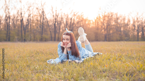 Young cheerful woman lie on the grass at sunset