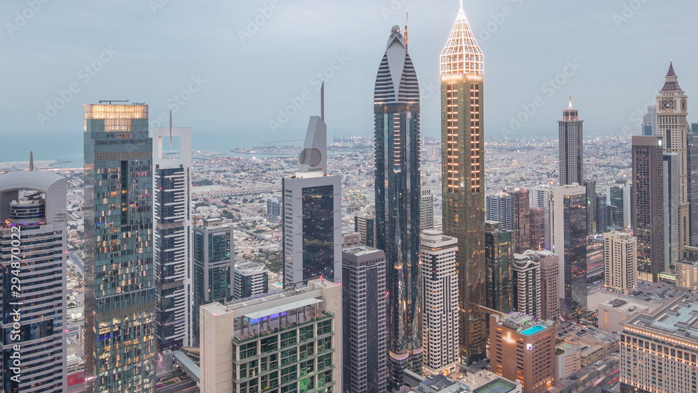 Fototapeta Skyline of the buildings of Sheikh Zayed Road and DIFC aerial day to night timelapse in Dubai, UAE.