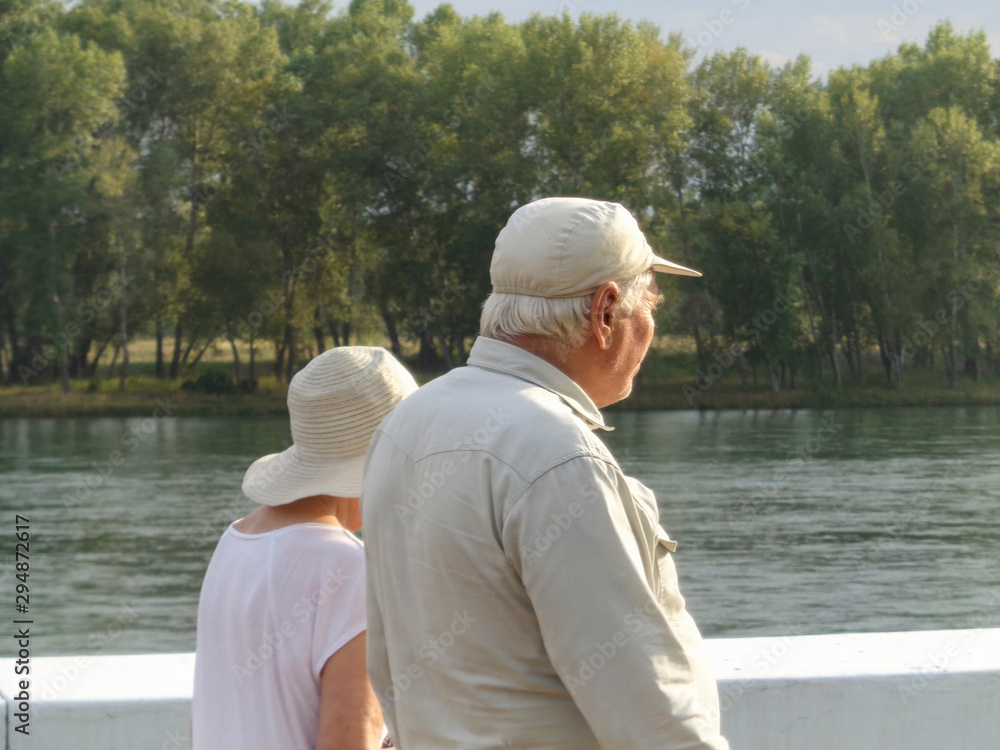 An elderly couple walking along the waterfront. Summer waterfront.