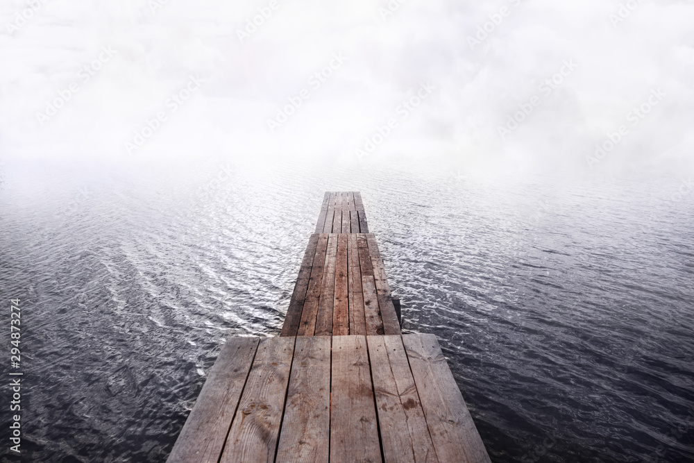 front view of wooden pier going into the water and fog,