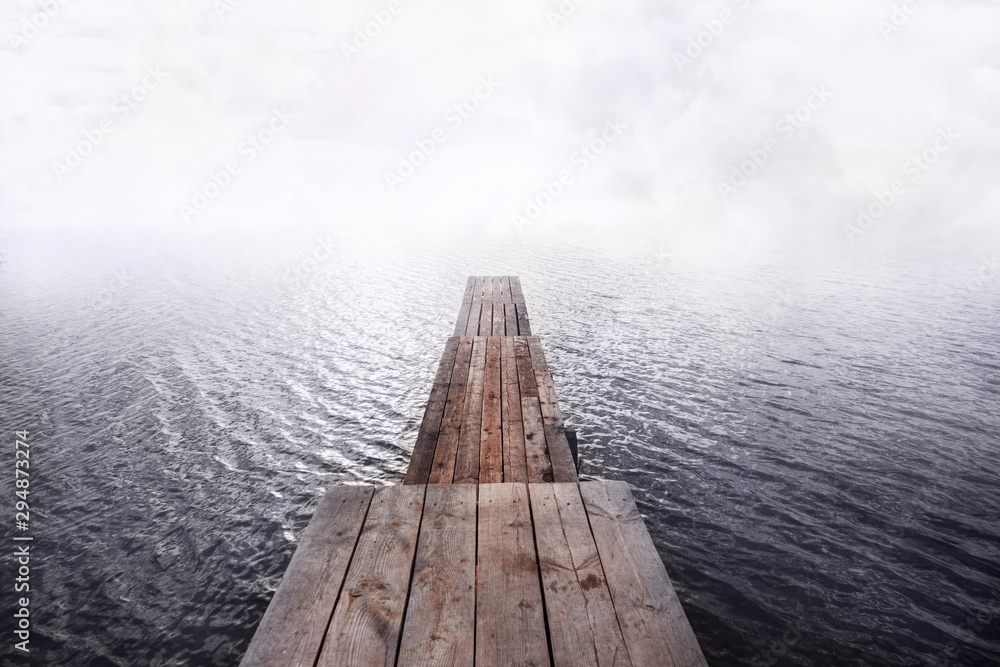 Obraz premium front view of wooden pier going into the water and fog,